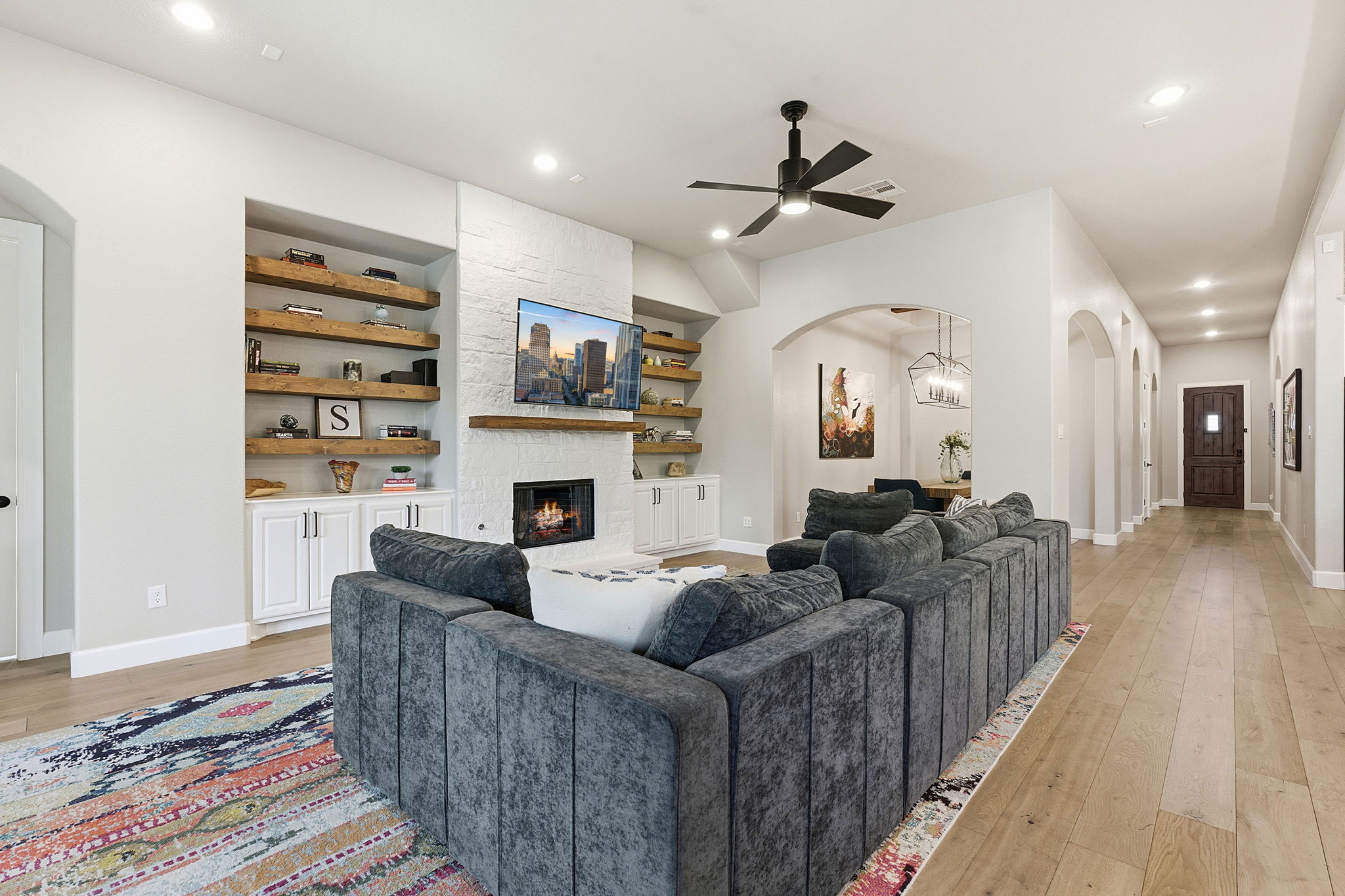 512 Choke Canyon Lane Georgetown, TX 78628 - Photo 4 of 37 Living area featuring arched walkways, built in features, light wood-type flooring, a stone fireplace, and recessed lighting