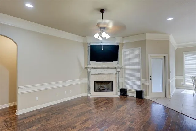 an empty room with fireplace wooden floor chandelier and windows