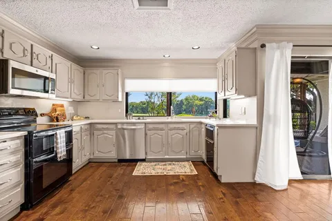 a kitchen with white cabinets a window and stainless steel appliances