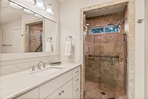 a bathroom with a granite countertop shower sink vanity and mirror