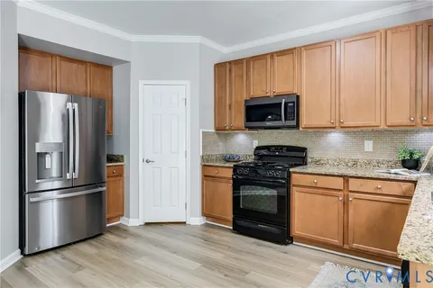 a kitchen with granite countertop wooden floors stainless steel appliances and a window