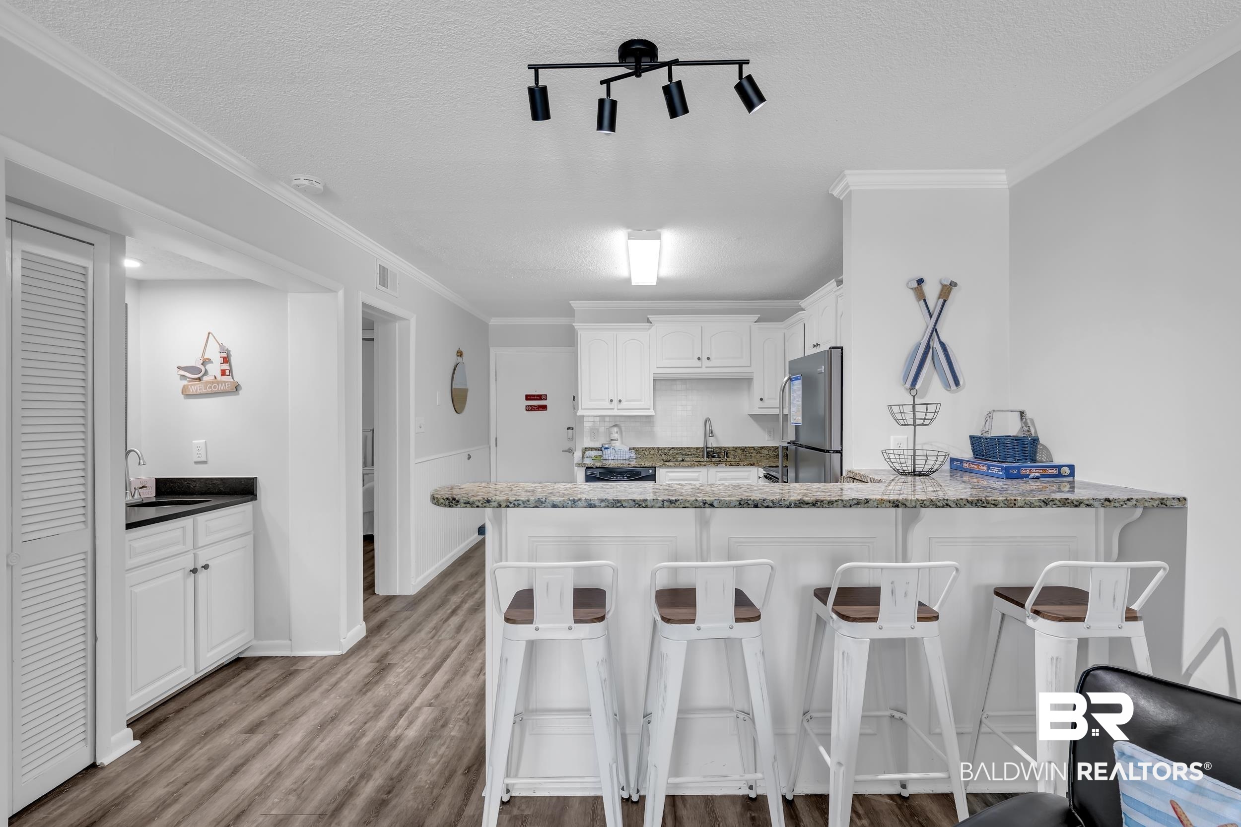 400 Plantation Road, Unit 2118 Gulf Shores, AL 36542 - Photo 8 of 59 Kitchen featuring a breakfast bar with stone-finish countertop, white cabinetry, and stainless steel appliances