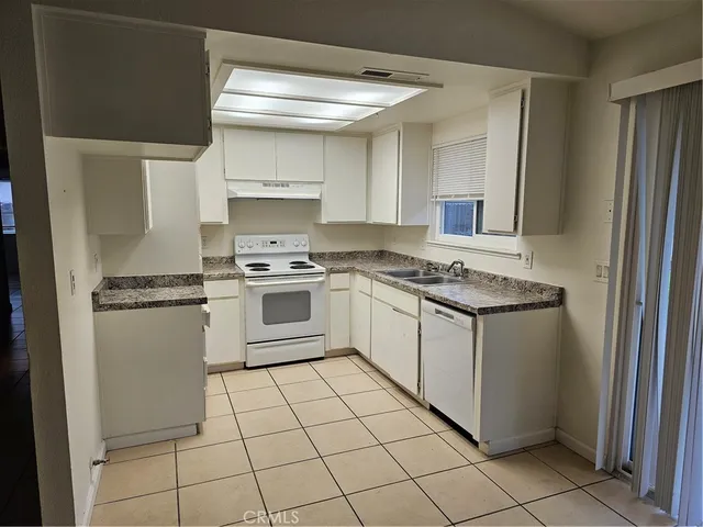 a white kitchen with a stove top oven and cabinets