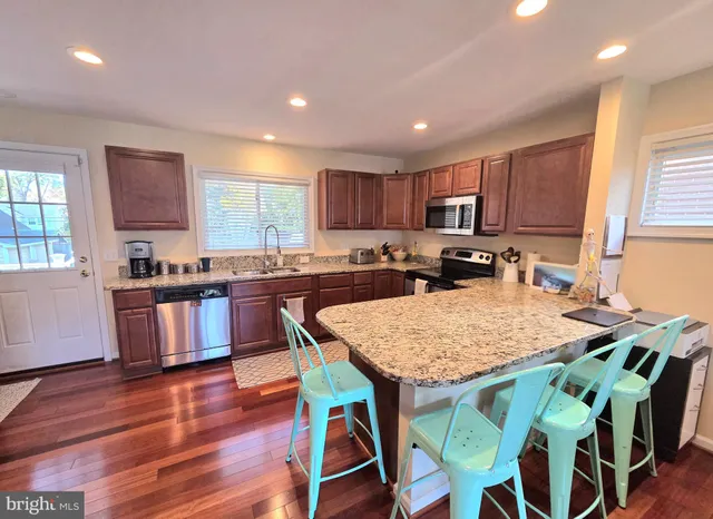 a kitchen with kitchen island granite countertop wooden floors cabinets a dining table and chairs