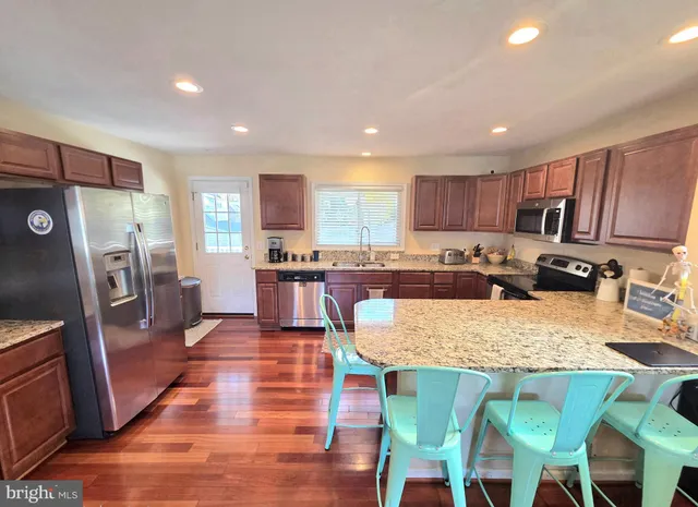 a kitchen with granite countertop stainless steel appliances a refrigerator a stove top oven and a center island