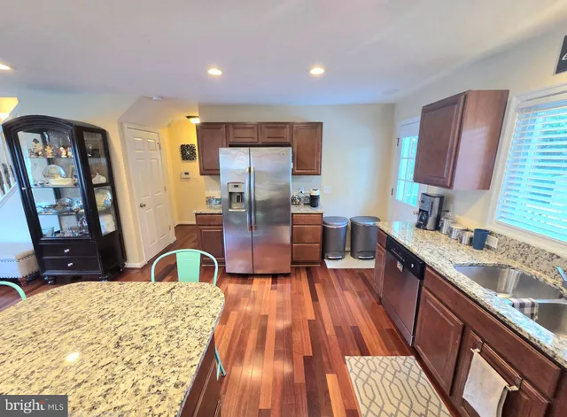 a large kitchen with kitchen island granite countertop a sink dishwasher stove and wooden cabinets