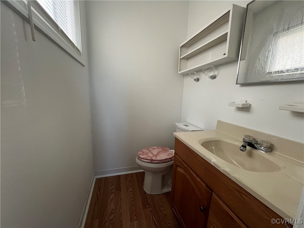 Half bathroom with toilet, baseboards, wood finish