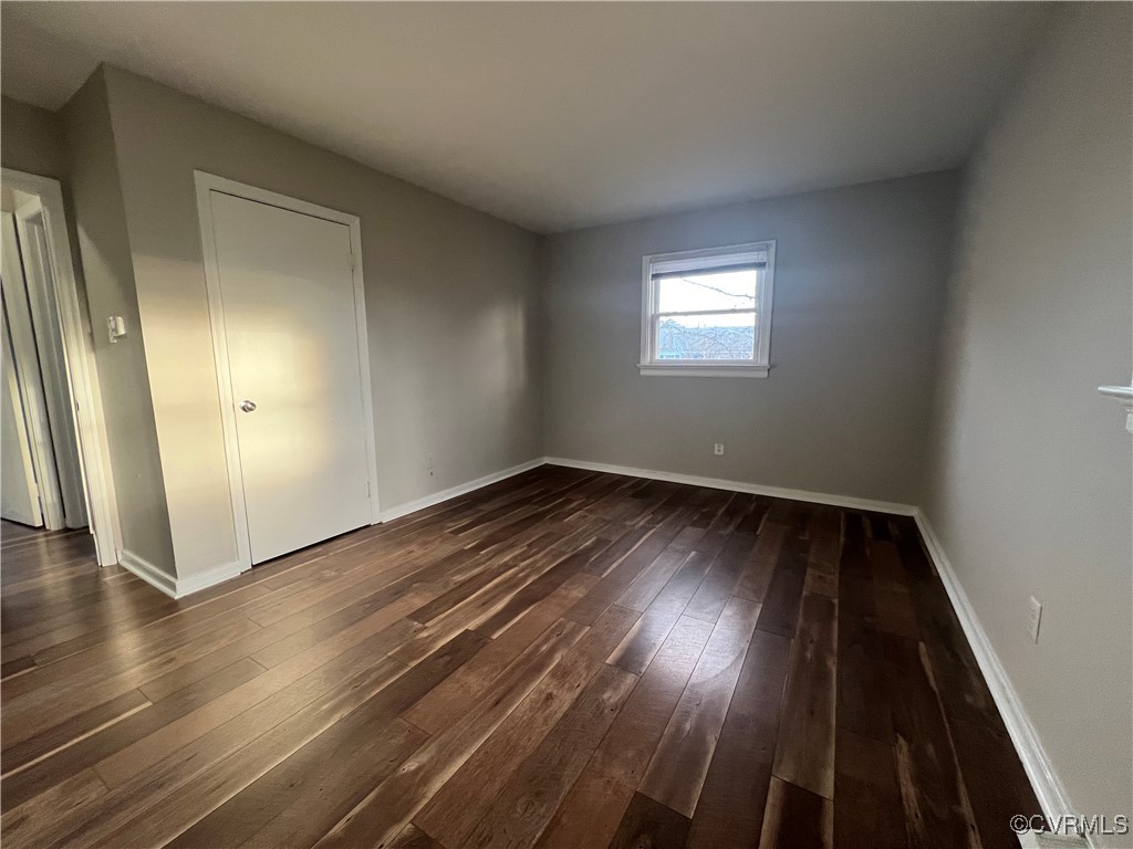 Unfurnished bedroom featuring baseboards and dark
