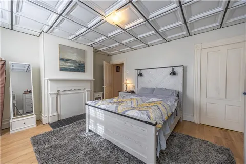 a bed sitting in a spacious bedroom next to a window