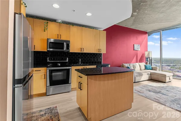 a kitchen with stainless steel appliances granite countertop a sink a stove a refrigerator a washer dryer and white cabinets