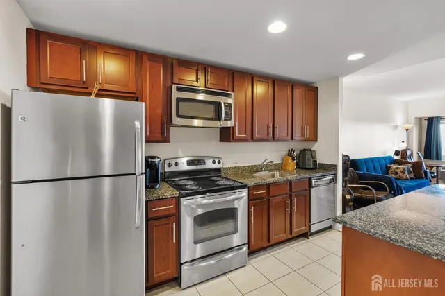 a kitchen with stainless steel appliances granite countertop a refrigerator sink stove microwave and cabinets