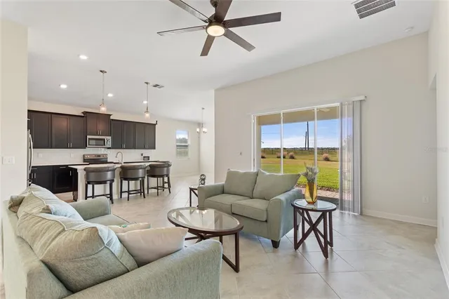 a kitchen with stainless steel appliances granite countertop a refrigerator a sink a stove a dining table and chairs