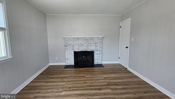 a view of empty room with wooden floor and fireplace