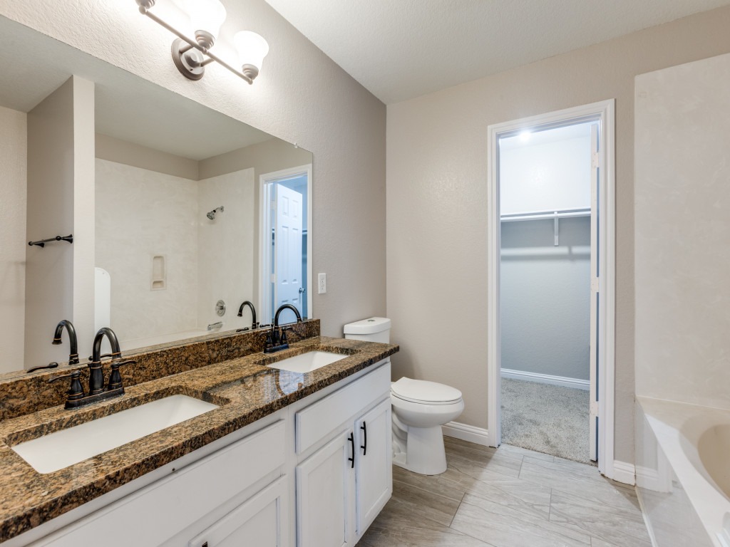 3005 Crownover Street Austin, TX 78725 - Photo 18 of 25 a bathroom with a granite countertop sink a toilet and a mirror
