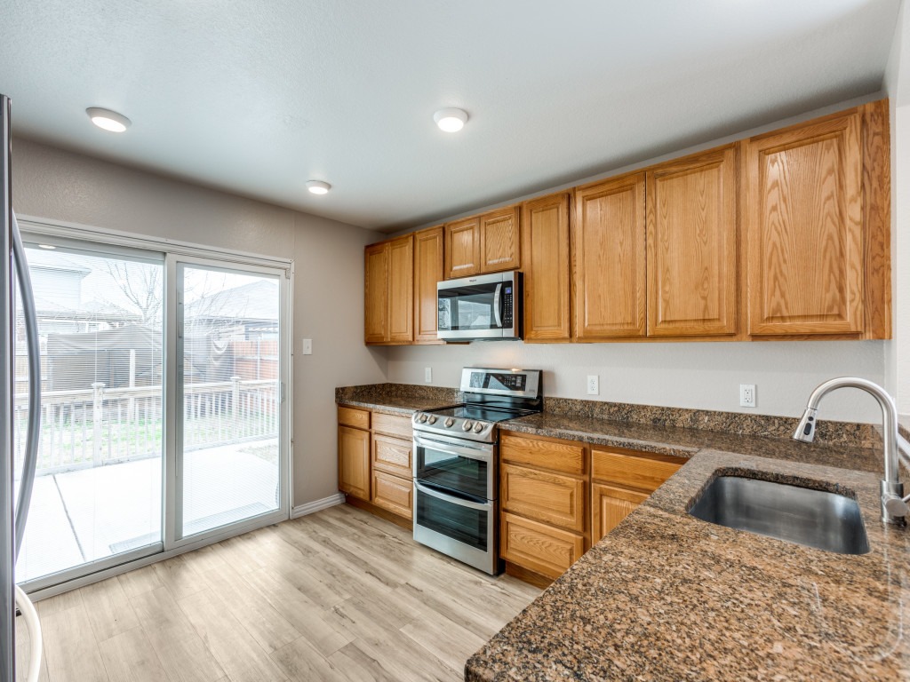 3005 Crownover Street Austin, TX 78725 - Photo 9 of 25 a kitchen with stainless steel appliances granite countertop a stove a sink and a refrigerator with wooden cabinets