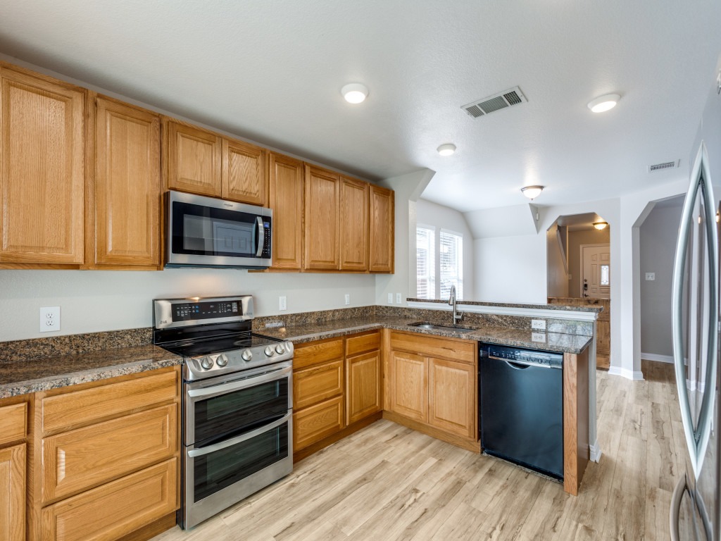 3005 Crownover Street Austin, TX 78725 - Photo 10 of 25 a kitchen with stainless steel appliances granite countertop wooden cabinets and a stove top oven