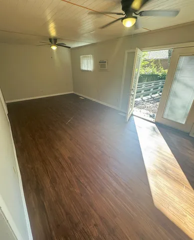 an empty room with wooden floor fan and windows