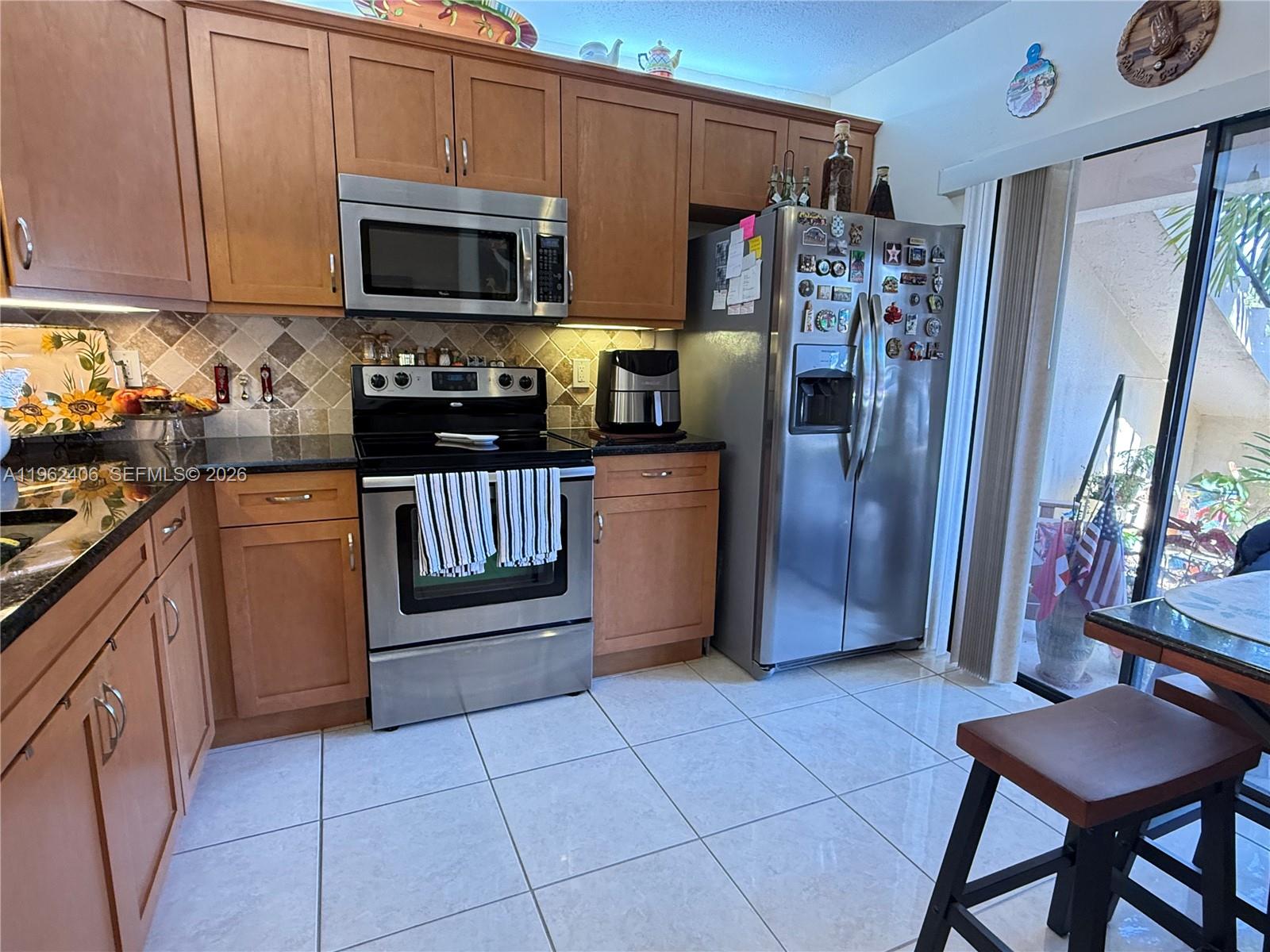 351 Club Circle, Unit 102 Boca Raton, FL 33487 - Photo 11 of 34 a kitchen with granite countertop a refrigerator and a stove top oven