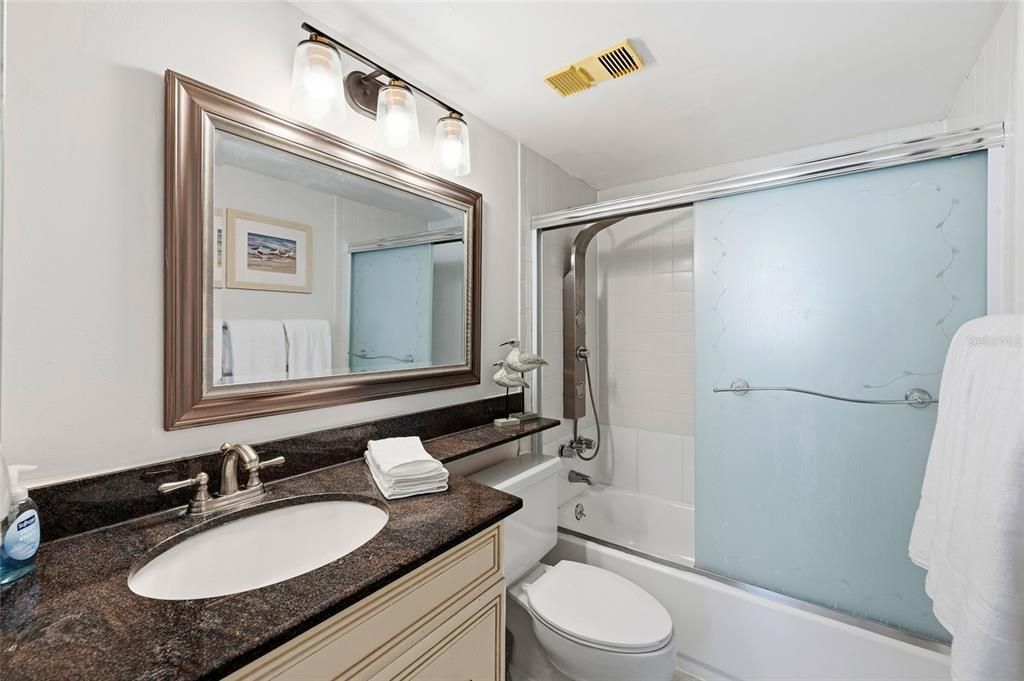 15462 Gulf Boulevard, Unit 601 Madeira Beach, FL 33708 - Photo 28 of 40 a bathroom with a granite countertop sink toilet a mirror and shower