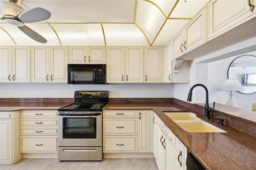 15462 Gulf Boulevard, Unit 601 Madeira Beach, FL 33708 - Photo 5 of 40 a kitchen with granite countertop a sink stainless steel appliances and cabinets