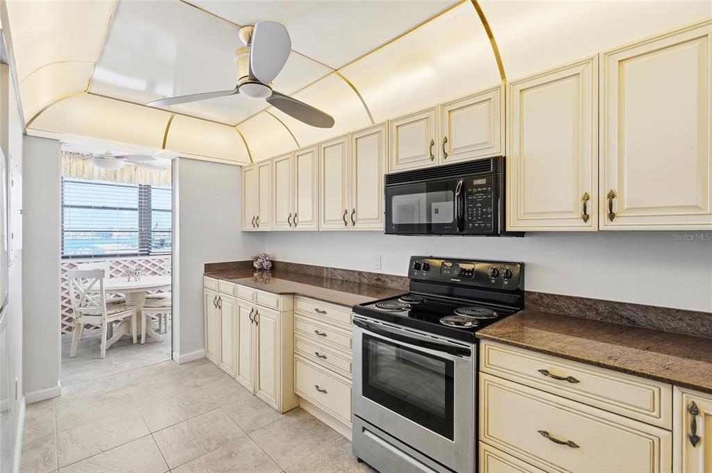 15462 Gulf Boulevard, Unit 601 Madeira Beach, FL 33708 - Photo 6 of 40 a kitchen with stainless steel appliances granite countertop a stove and a microwave