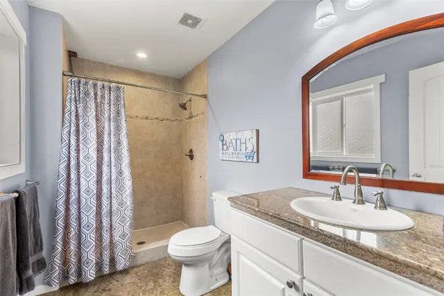 a bathroom with a granite countertop sink toilet and shower