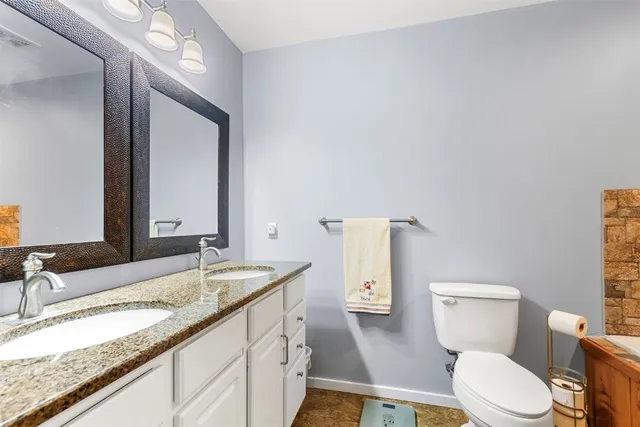 a bathroom with a granite countertop toilet sink and mirror