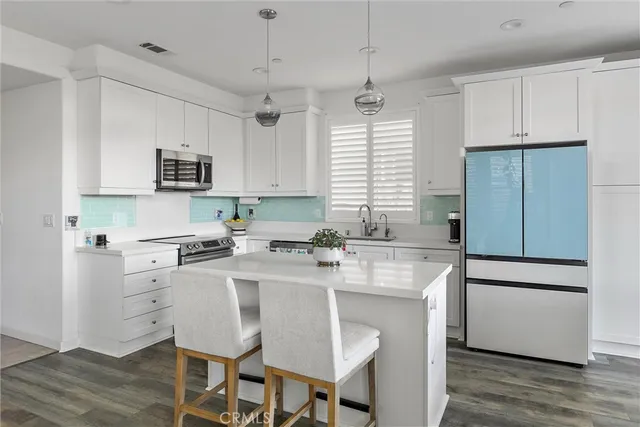 a kitchen with stainless steel appliances granite countertop a stove a refrigerator a microwave a sink a stove and white cabinets with wooden floor