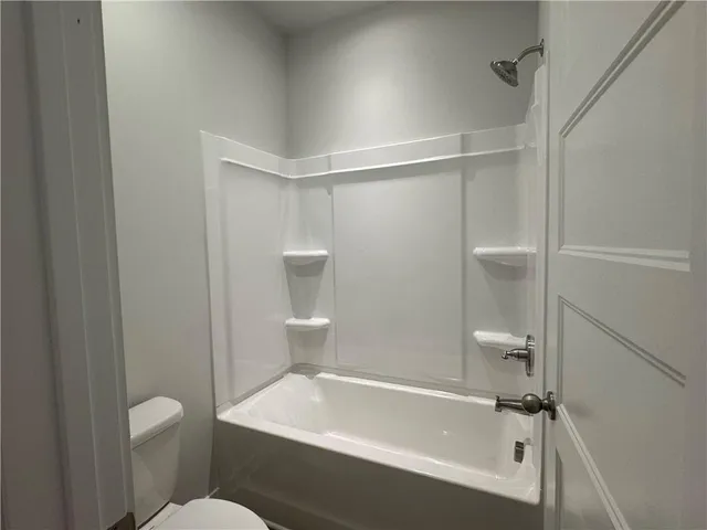a bathroom with a granite countertop bathtub shower and toilet