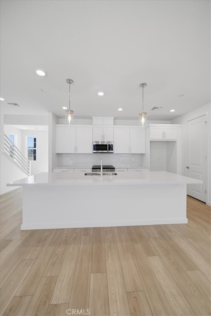 4852 Arroyo Run Moorpark, CA 93021 - Photo 37 of 39 a view of kitchen with kitchen island white cabinets wooden floor and stainless steel appliances