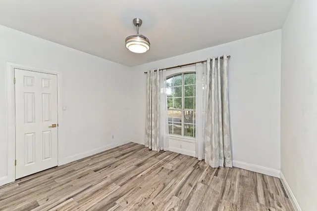 a view of a refrigerator in kitchen and an empty room