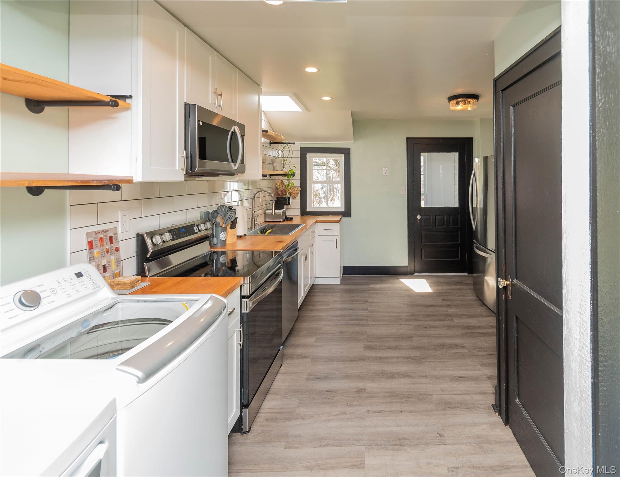 680 Old Rte 17 Livingston Manor, NY 12758 - Photo 6 of 29 a kitchen with stainless steel appliances a stove top oven a sink a refrigerator white cabinets and wooden floor