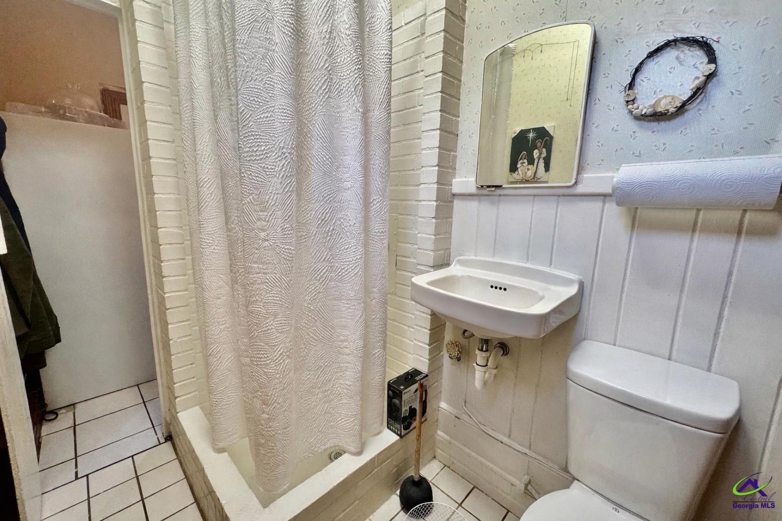 914 Adderton Street Americus, GA 31719 - Photo 50 of 53 a bathroom with a sink a toilet a mirror and shower curtain