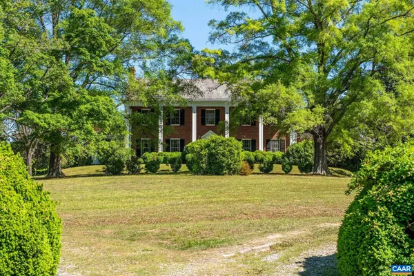 a view of a white house with a large tree