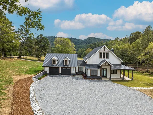 an aerial view of a house with swimming pool and big trees