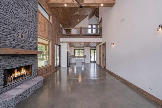 a view of an empty room with wooden floor fireplace and a window