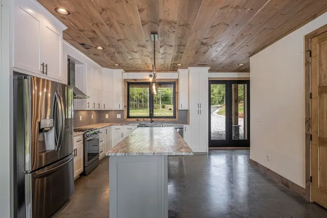 a kitchen with stainless steel appliances granite countertop a refrigerator a stove and a wooden floors