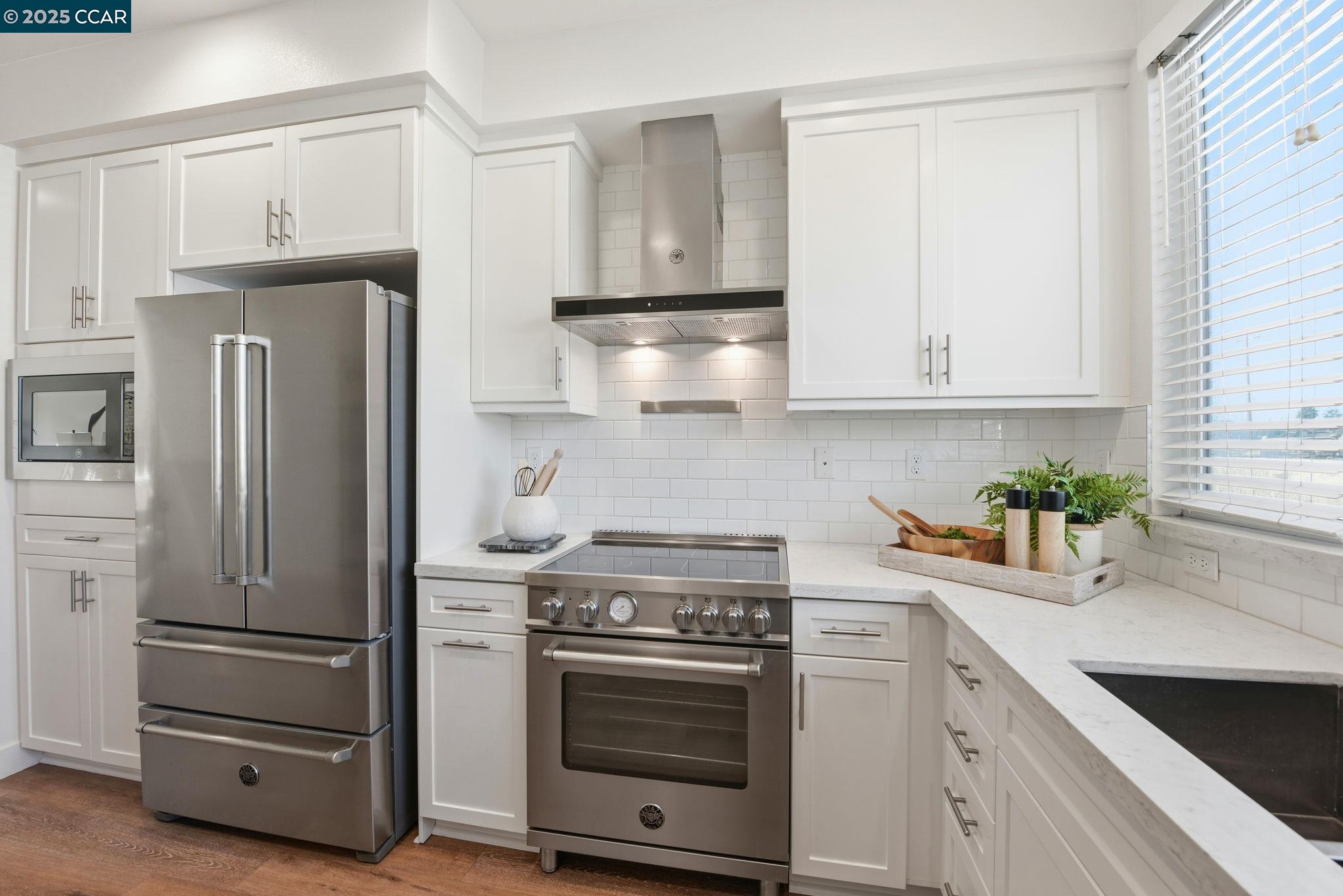 967 24th Street Oakland, CA 94607 - Photo 16 of 43 a kitchen with stainless steel appliances white cabinets and a stove a refrigerator with wooden floor