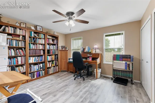 a view of a workspace with bookshelf and a window