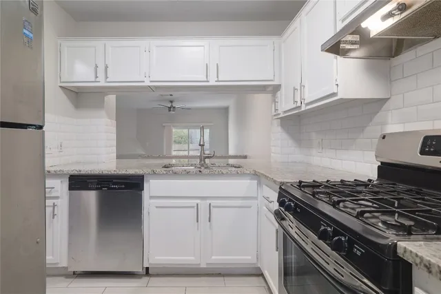 a kitchen with white cabinets and appliances
