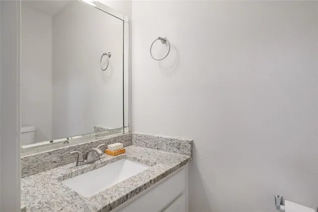 a bathroom with a granite countertop sink and a mirror
