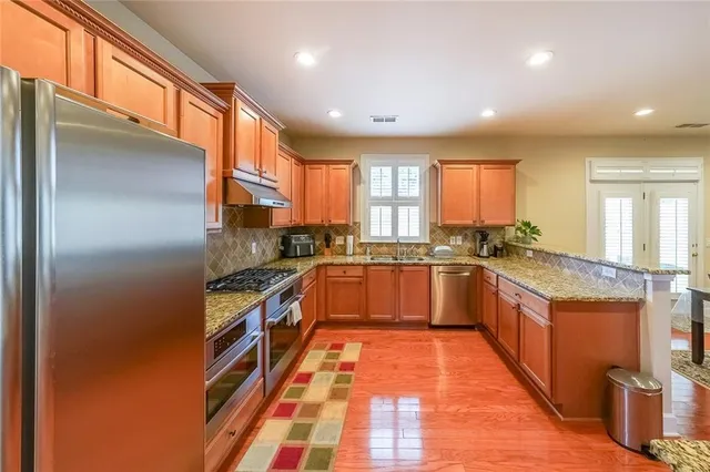a kitchen with stainless steel appliances granite countertop a stove a sink and a refrigerator