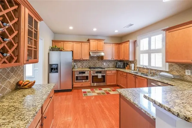 a large kitchen with stainless steel appliances granite countertop a refrigerator a stove and a sink with cabinets
