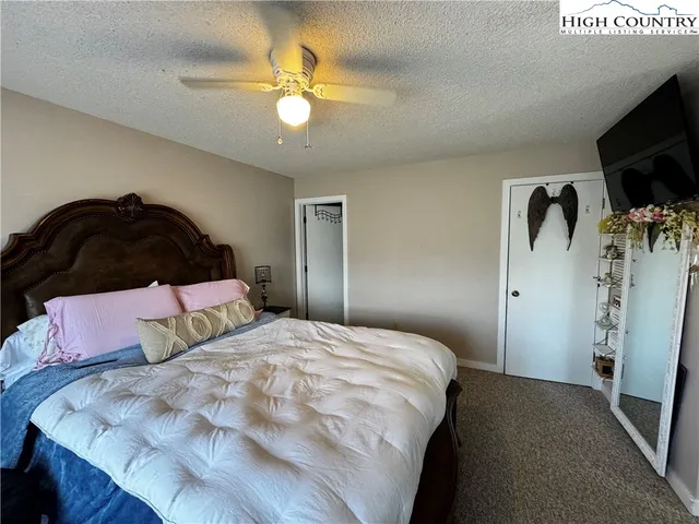 a bedroom with a bed and a flat tv screen on dresser