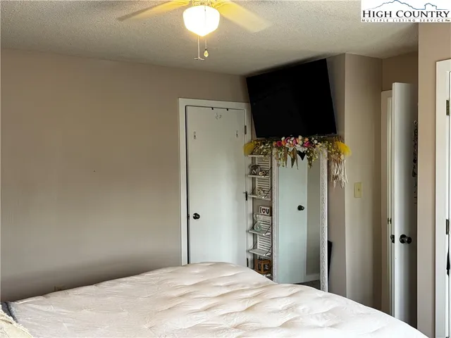 a bedroom with a bed and a flat tv screen on wall