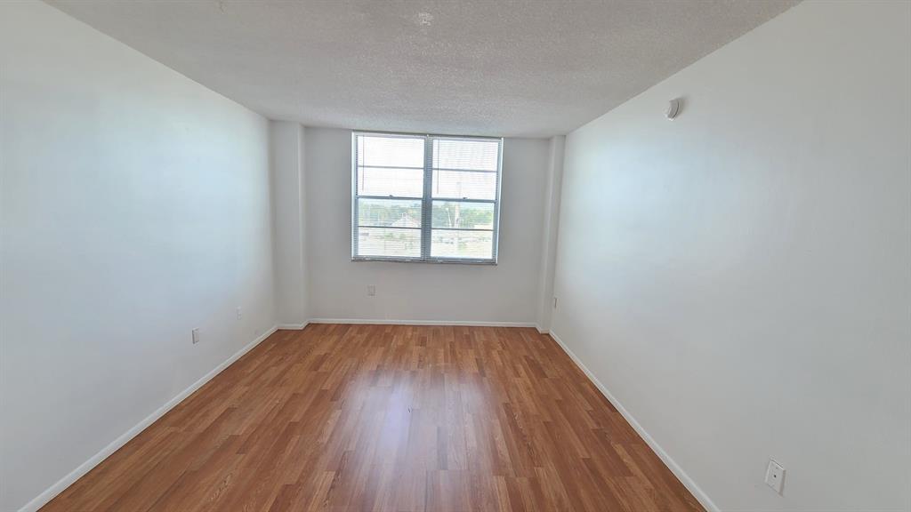 15600 Northwest 7th Avenue, Unit 606 Miami, FL 33169 - Photo 5 of 13 an empty room with wooden floor and windows