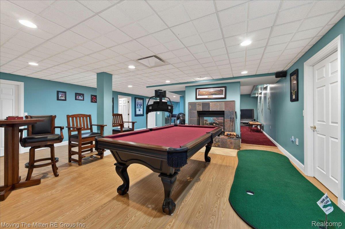 39750 Willow Road New Boston, MI 48164 - Photo 35 of 68 Recreational area featuring a built-in stone-clad fireplace, wood-finish flooring, recessed lighting, and a putting green