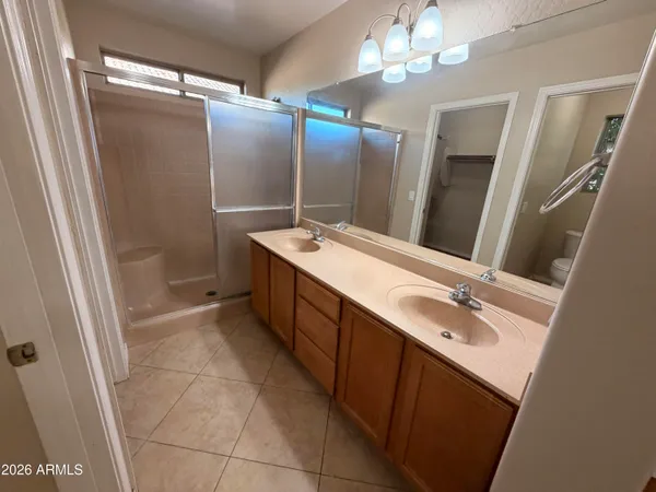 a spacious bathroom with a double vanity sink a large mirror and a shower