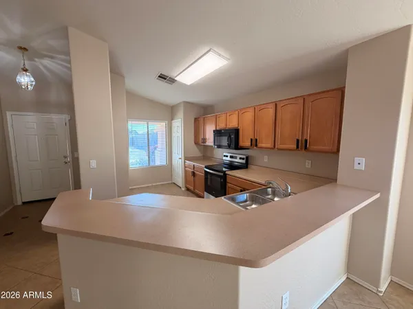 a kitchen with granite countertop a sink a stove top oven a refrigerator cabinets and wooden floor