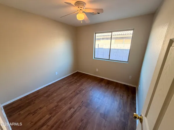 an empty room with wooden floor fan and windows